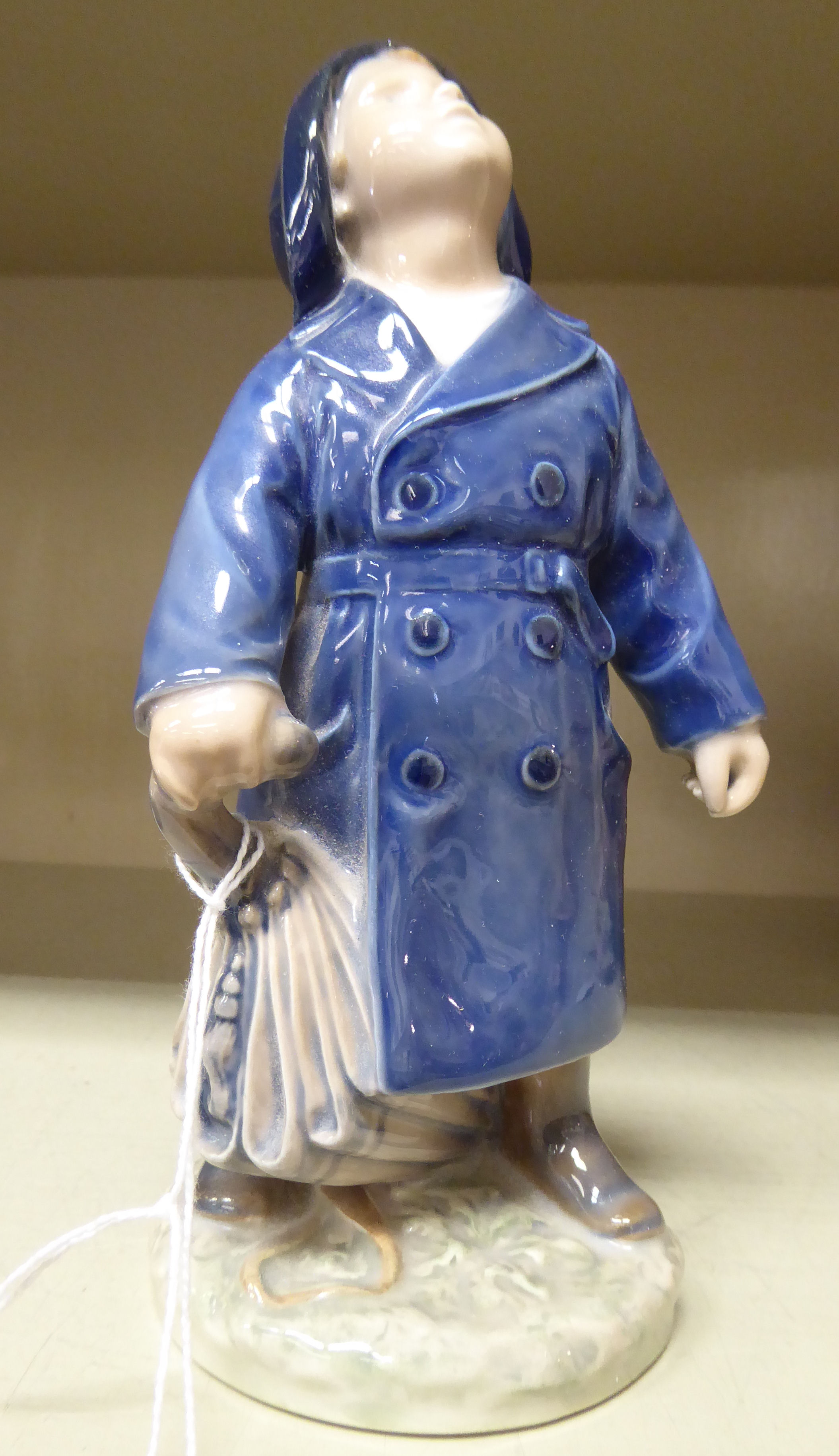 A Royal Copenhagen porcelain figure, a boy wearing a blue raincoat, holding an umbrella, model no.