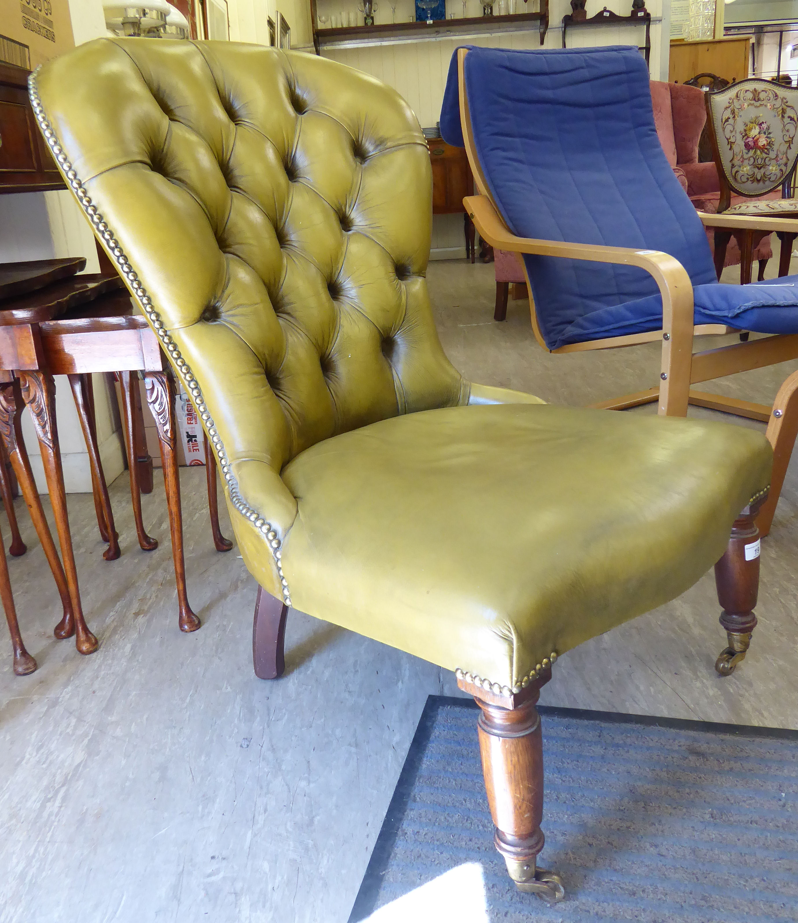 A Victorian style low, spoonback chair, stud and part button upholstered in olive coloured hide,