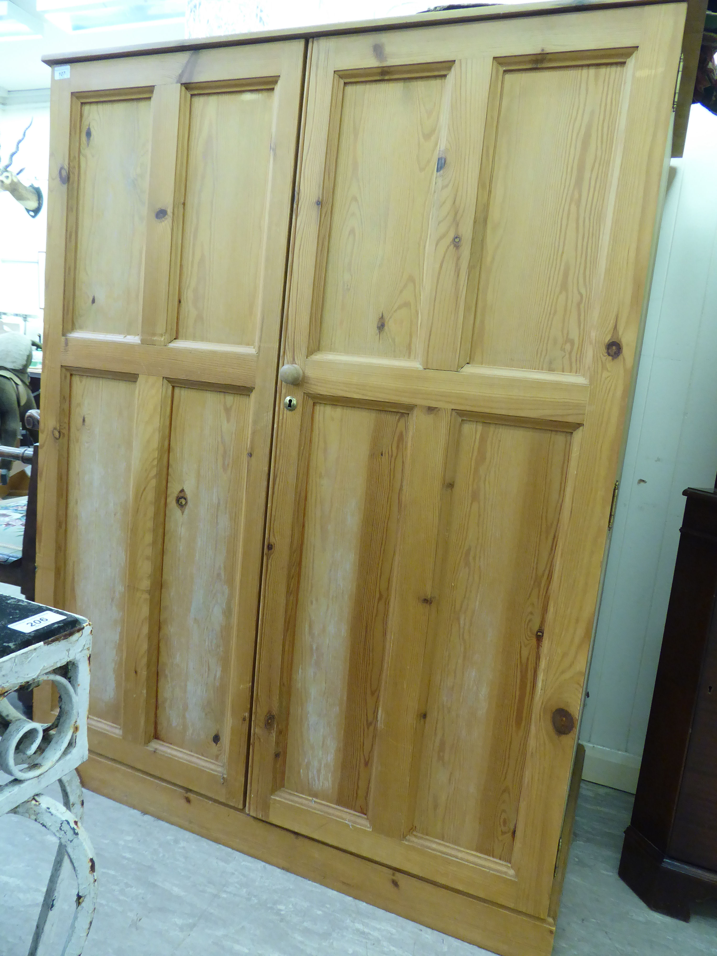 A modern stripped pine cupboard with a pair of panelled doors,