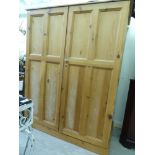 A modern stripped pine cupboard with a pair of panelled doors,