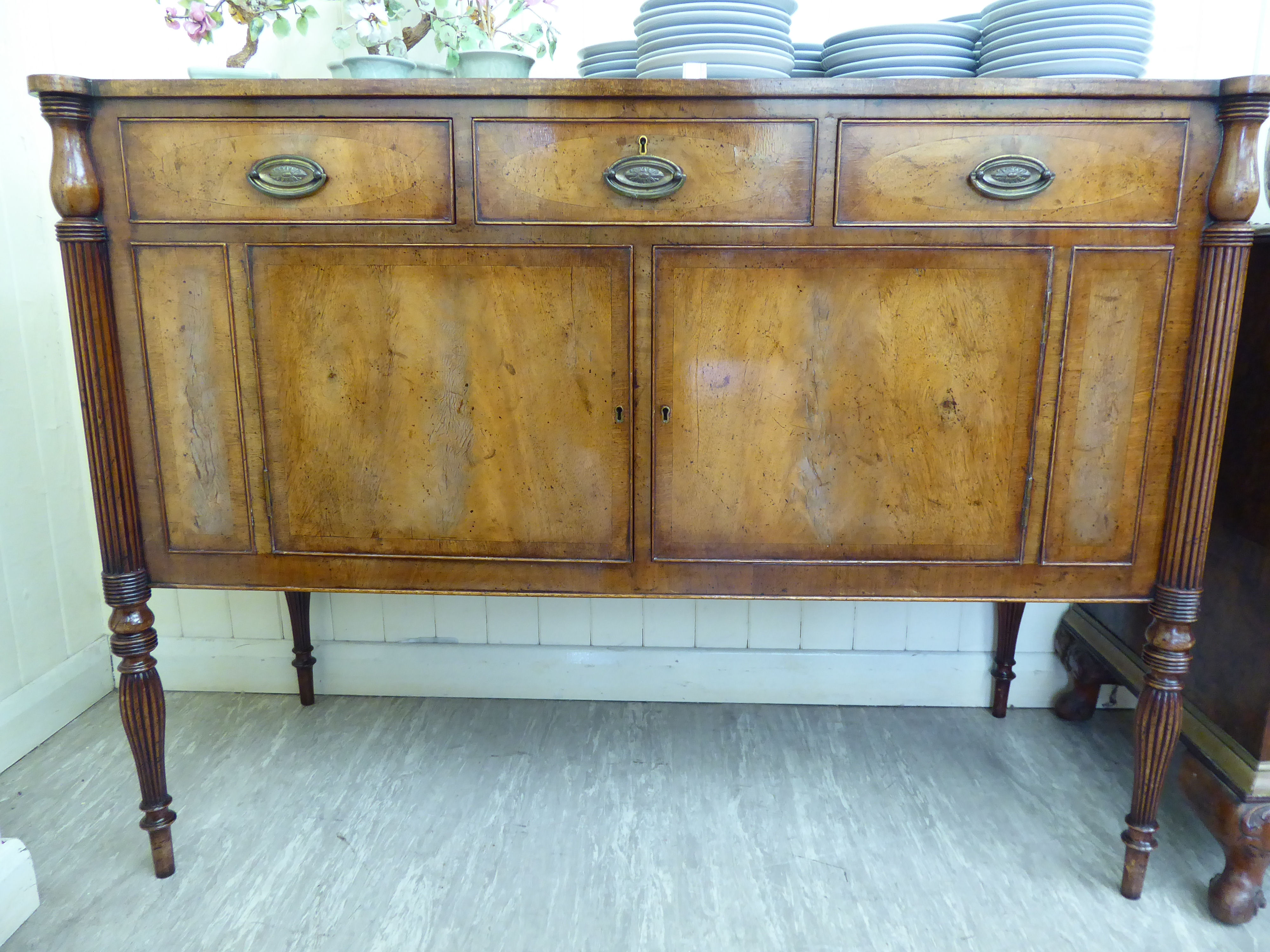 A Maple reproduction of a George III crossbanded mahogany sideboard with three frieze drawers,