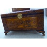 A modern profusely carved camphorwood chest with pictorial panels and straight sides,