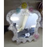 An early 20thC Venetian glass table mirror, set in a C-scrolled and foliate frame,