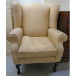 A mid 20thC Georgian style wingback armchair, upholstered in a foliate beige fabric,