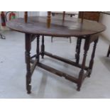 A George III stained oak drop leaf table, raised on baluster and block supports,