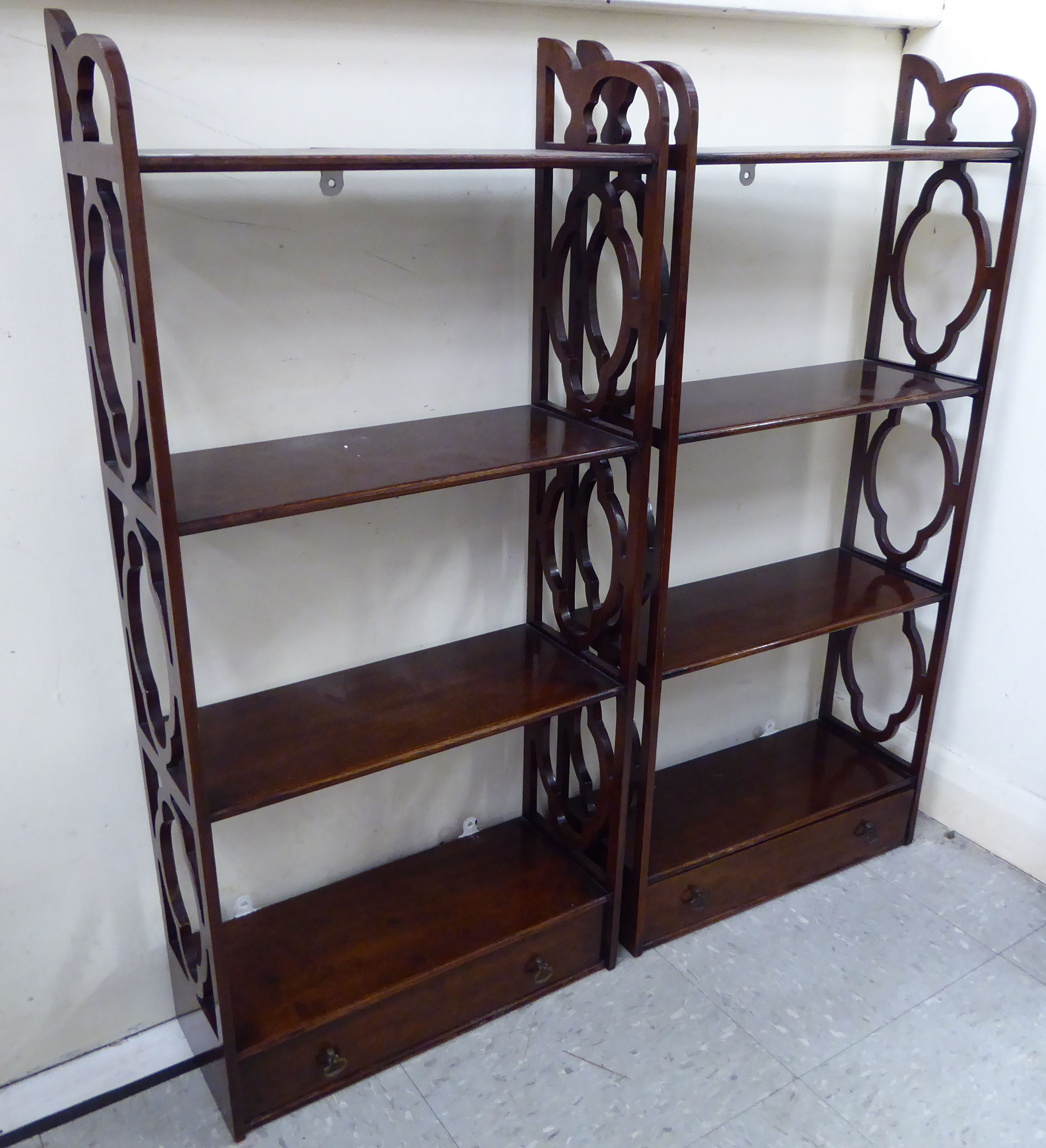 A pair of Georgian style mahogany hanging four tier shelves with uniformly fretworked sides,