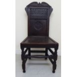 A mid 18thC oak framed side chair with a relief carved, panelled back incorporating IHS,