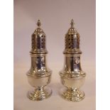 A pair of Georgian style silver pepper pots of pedestal vase design, the perforated,