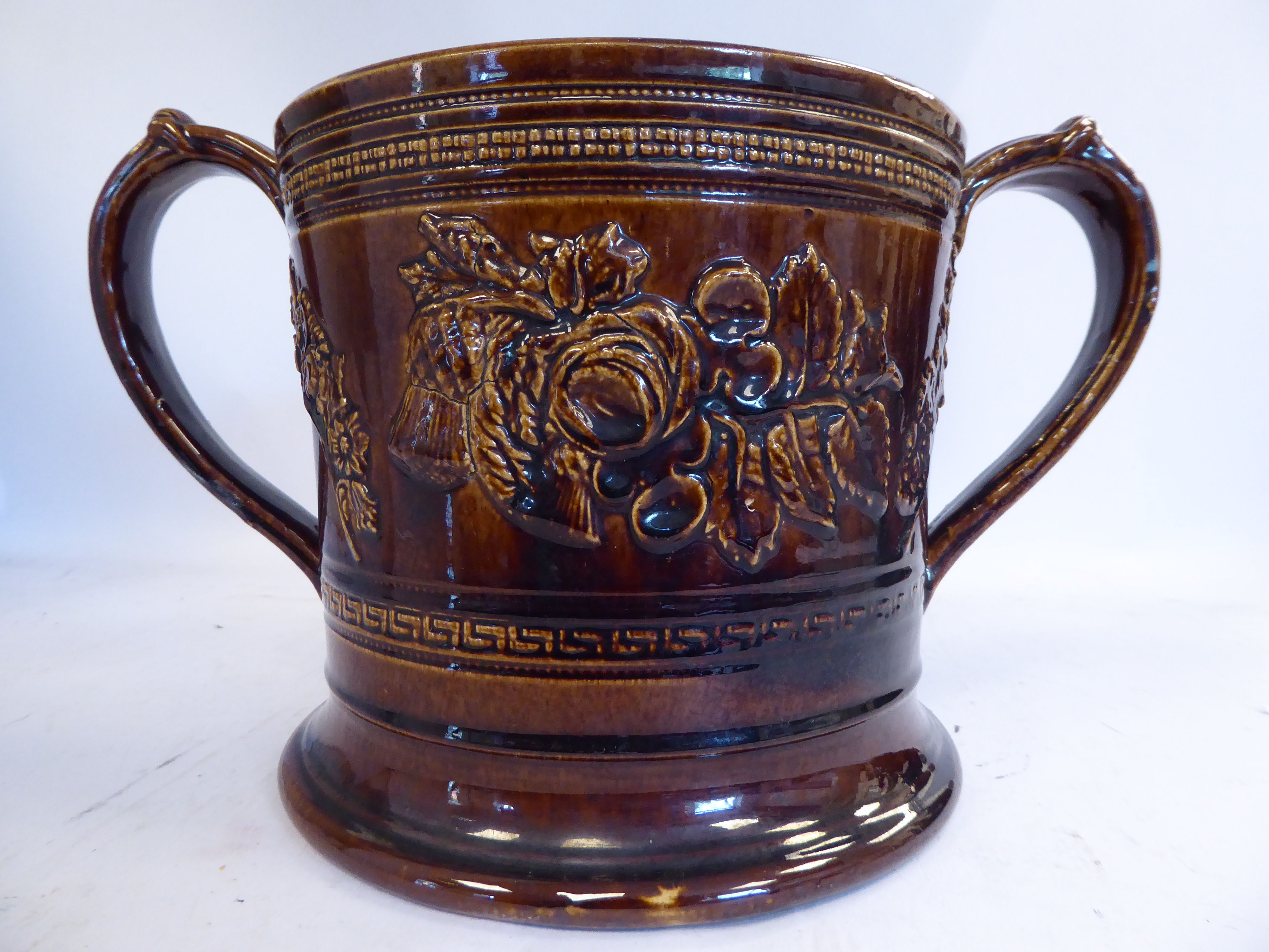 A mid 19thC treacle glazed earthenware 'oversize' loving cup with straight sides,