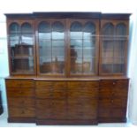 An early Victorian mahogany breakfront library bookcase with a level cornice, over four in-line,