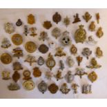 Approximately fifty-five military cap badges and other insignia,