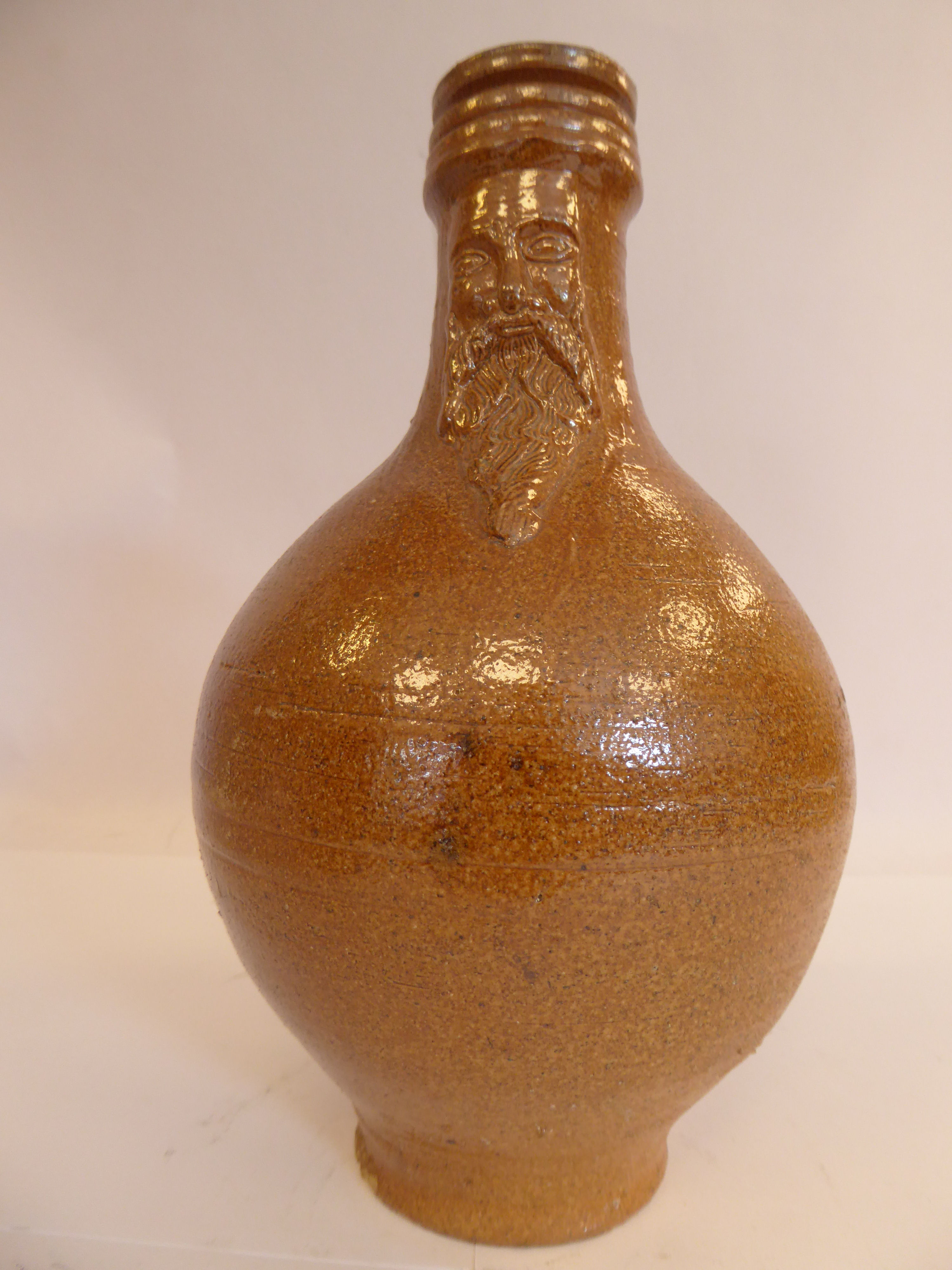 An 'antique' Continental salt glazed bellarmine of ovoid form with a strap handle bears an