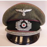 A World War II German Army peaked cap with a pressed metal eagle and swastika