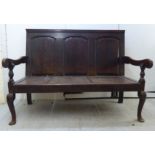 A late 18thC country made oak settle with a level, high, fielded, tri-panelled back, open arms,