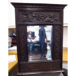 An early 20thC mirror, the bevelled plate set in a wide, panelled and relief carved oak frame,