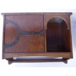 An early 20thC honey coloured oak hanging cabinet, in the manner of Liberty, comprising a lockable,
