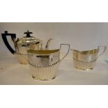 A late Victorian bachelor's matched three piece silver tea set of oval, demi-reeded design,