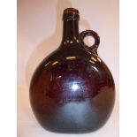 A 19thC semi-opaque dark amber coloured glass wine bottle of flattened form with a strap handle and