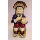 An early 19thC Staffordshire pottery Toby jug, the seated figure wearing a tricorn hat,