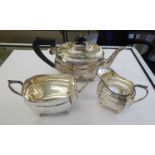 A matched three piece silver tea set of panelled, oval,