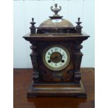 An early 20thC carved walnut cased American mantel clock with a domed top and finials;