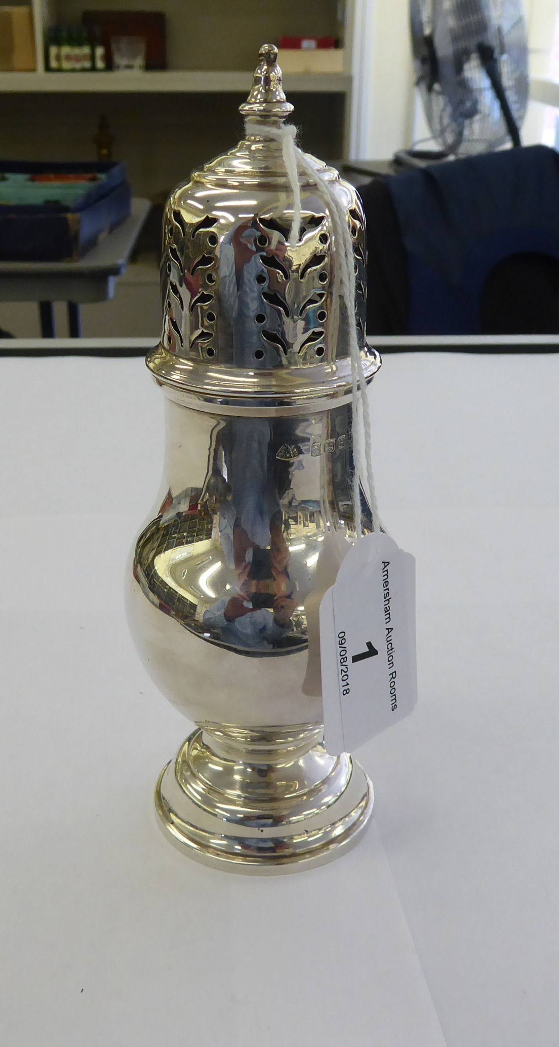 A silver caster of pedestal vase design with a perforated,