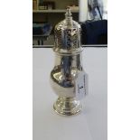 A silver caster of pedestal vase design with a perforated,