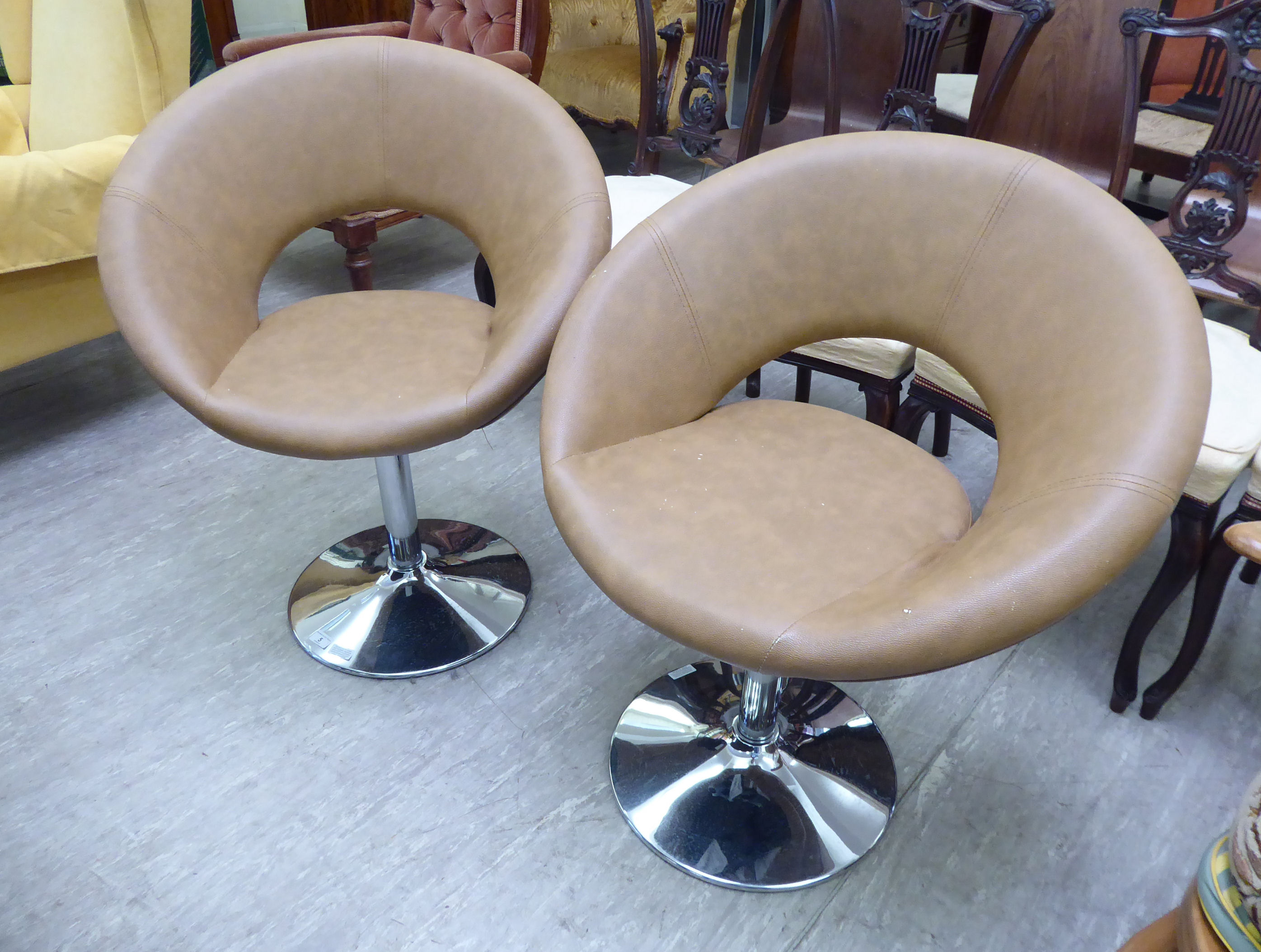 A pair of modern faux brown hide upholstered swivel chairs,