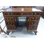 A 1930s burr walnut veneered twin pedestal desk, having a brass galleried border,