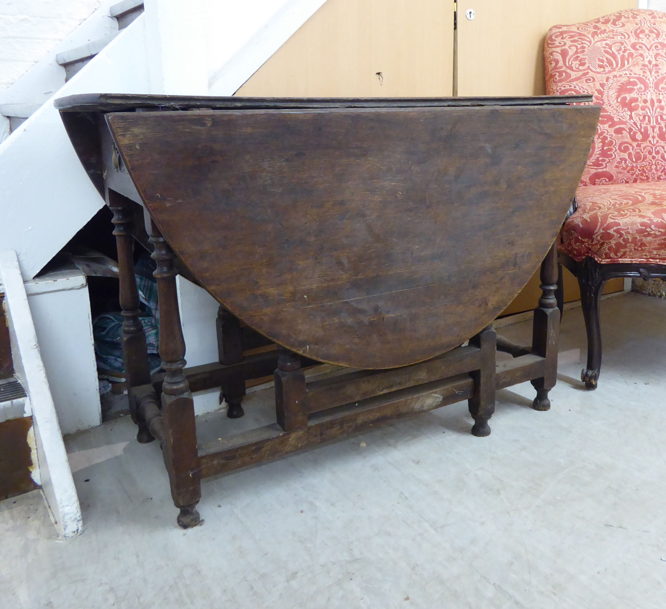 A George III stained oak drop leaf table, raised on baluster and block supports,