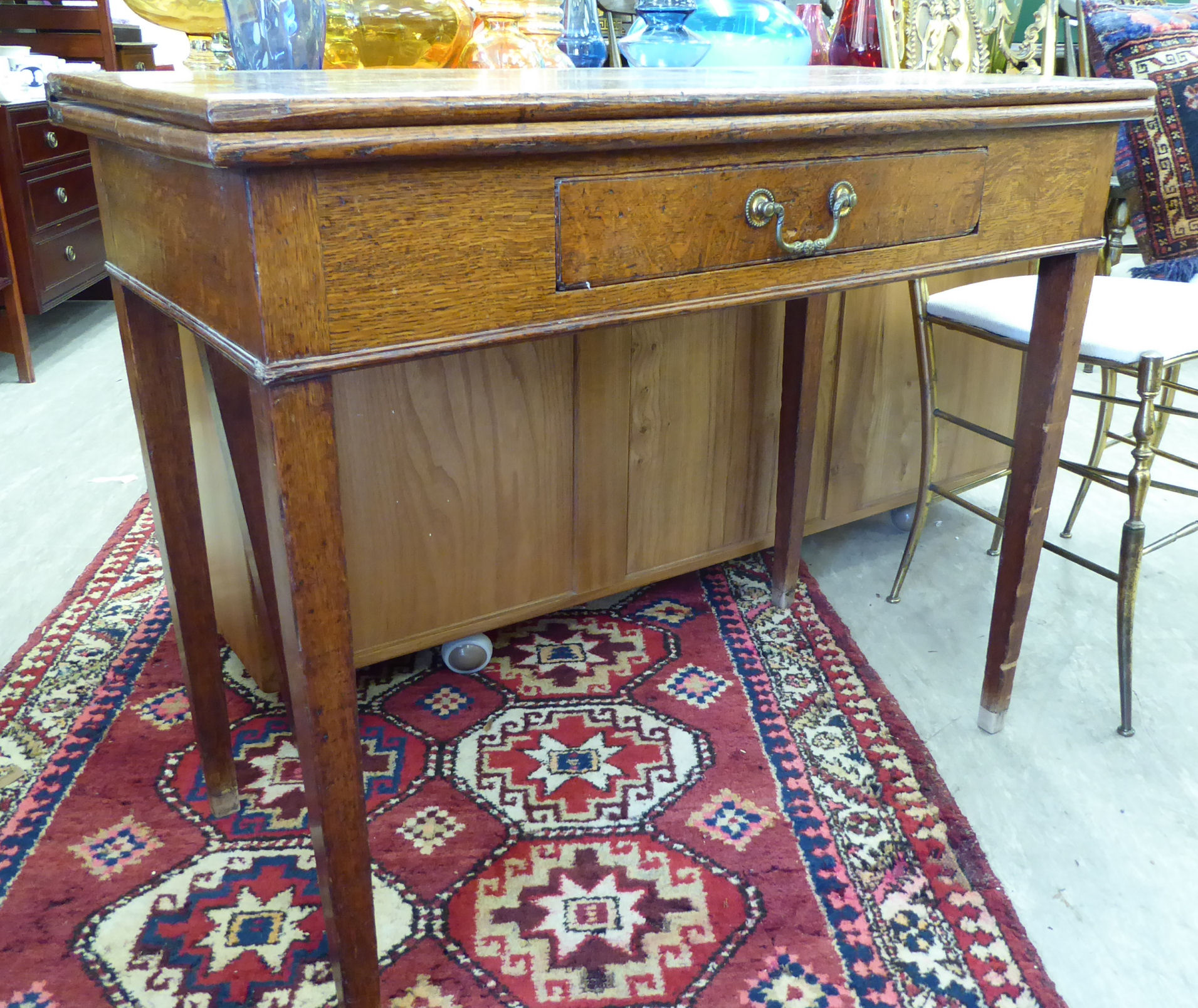 An early 19thC honey coloured oak tea table, the rectangular, foldover top above a frieze drawer,