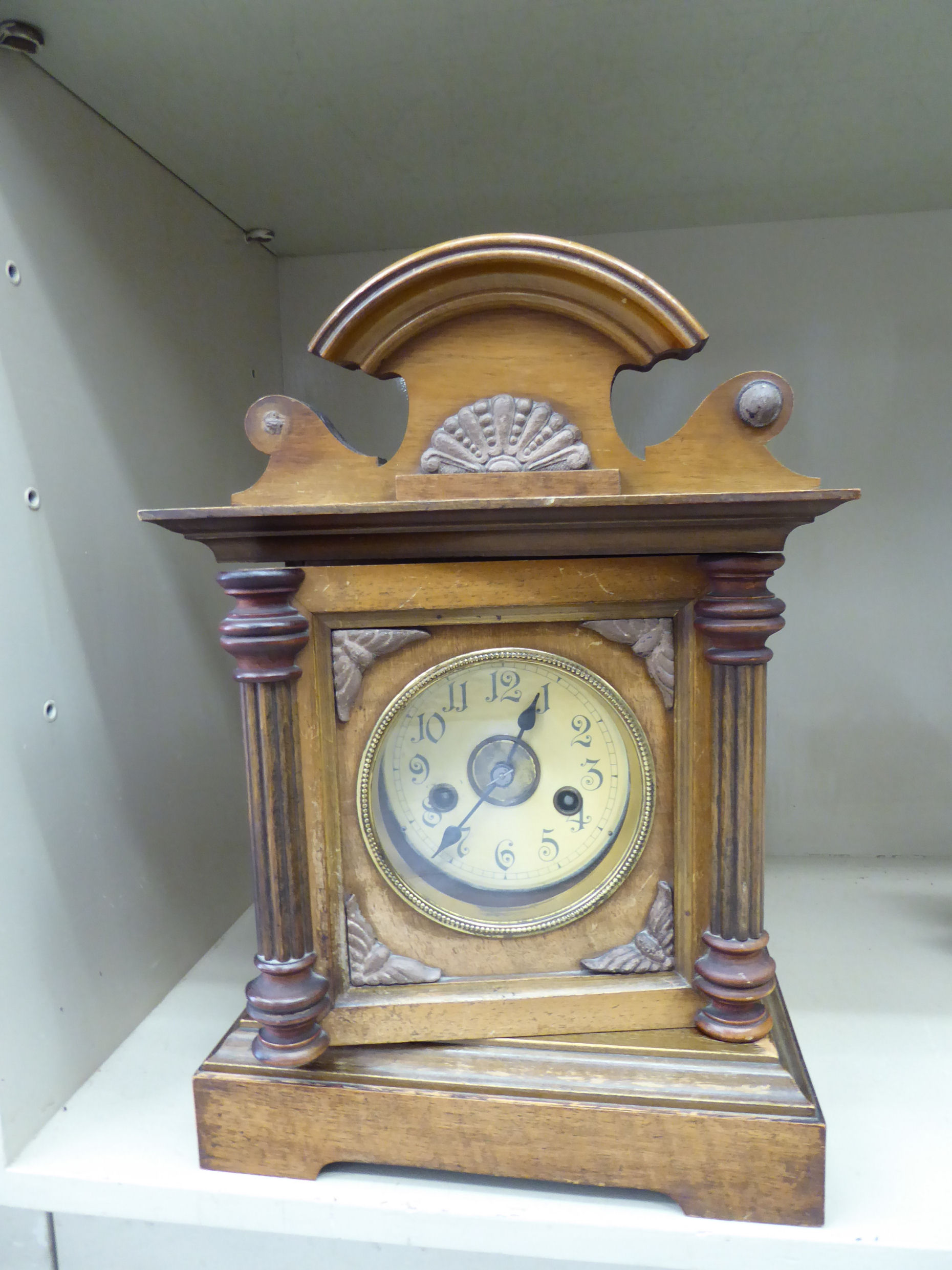 An early 20thC walnut cased mantel clock with an arched crest and pilaster flanks,