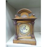 An early 20thC walnut cased mantel clock with an arched crest and pilaster flanks,