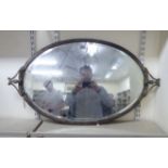 An early 20thC oval, bevelled mirror,
