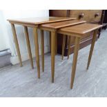 A nesting set of three 1960s/70s teak and beech occasional tables, raised on turned,