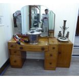 A 1930s light oak dressing table, surmounted by a triptych mirror, on a bow front,