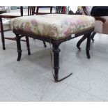 A late 19thC ebonised square stool with a braided, floral fabric upholstered, overstuffed seat,