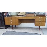 A mid 20thC teak effect seven drawer twin pedestal dressing table,
