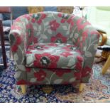 A modern multi-coloured floral fabric covered tub chair with a carved back, raised on tapered,