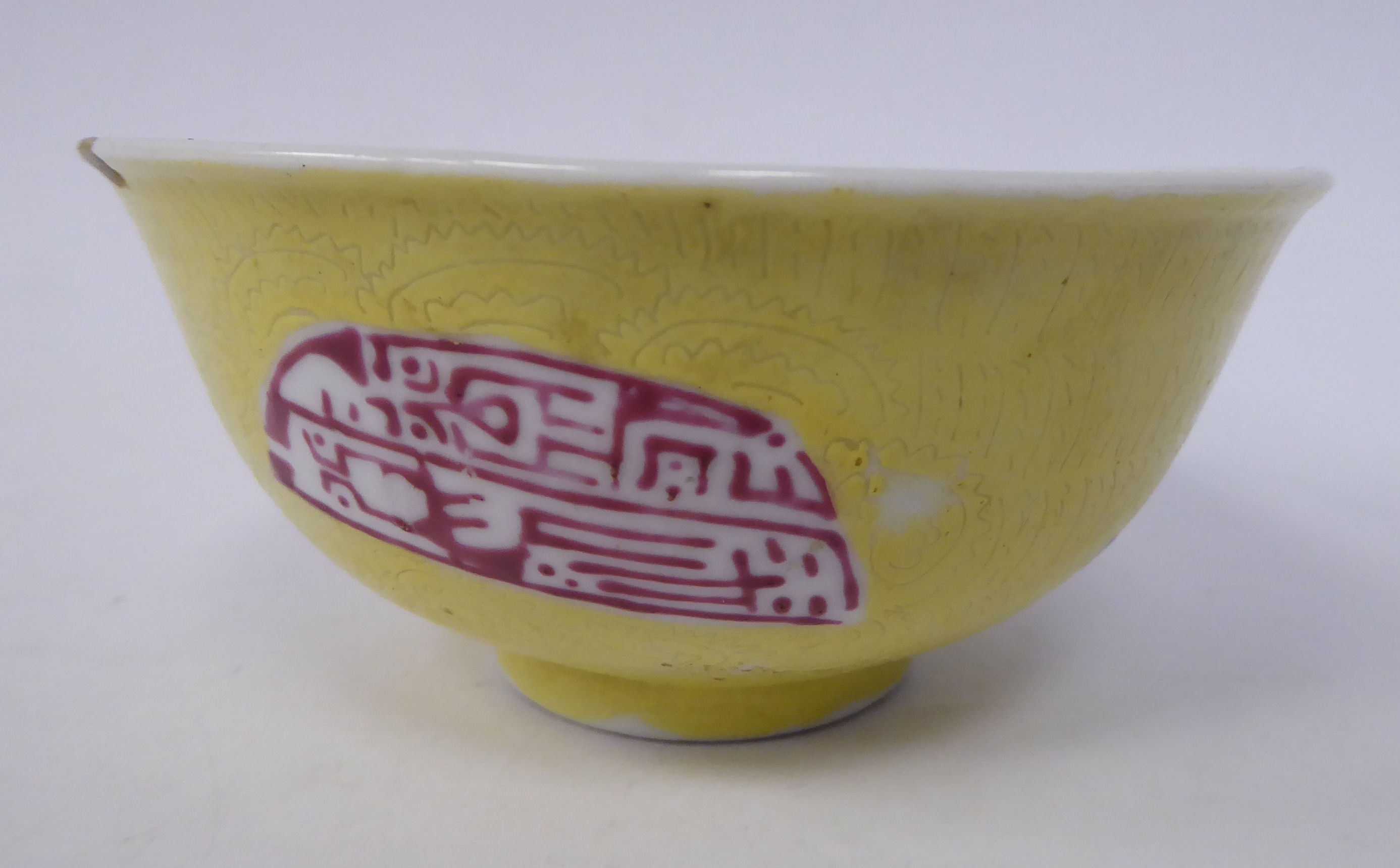 A late 19thC Chinese yellow glazed footed bowl, decorated with scrafitto inscribed ornament,