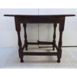 A late 18thC country made, dowelled oak side table with an overhanging, planked top,