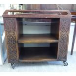 A 1930s oak dinner wagon with scroll carved floral and lunette ornament,