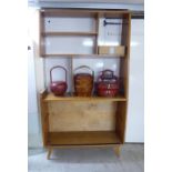 A mid 20thC light oak living room unit with a staggered arrangement of open shelves and glazed