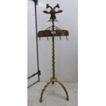 A mid 20thC cast brass fireside companion stand, surmounted by a winged creature, over four hooks,