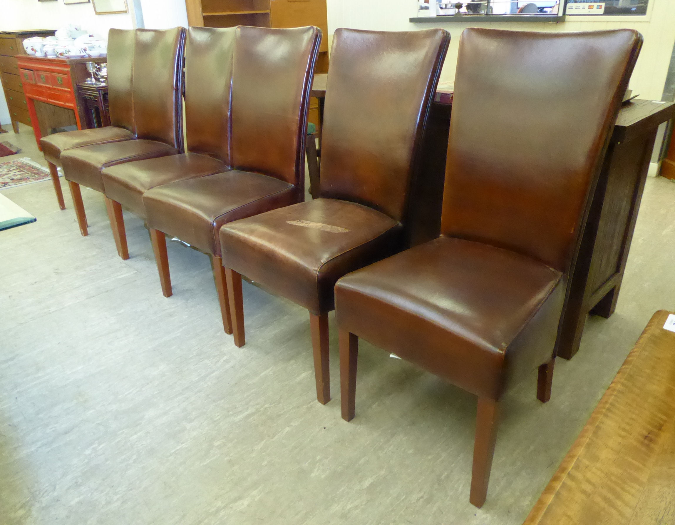 A set of six modern dining chairs, the stitched brown hide backs and seats raised on square,