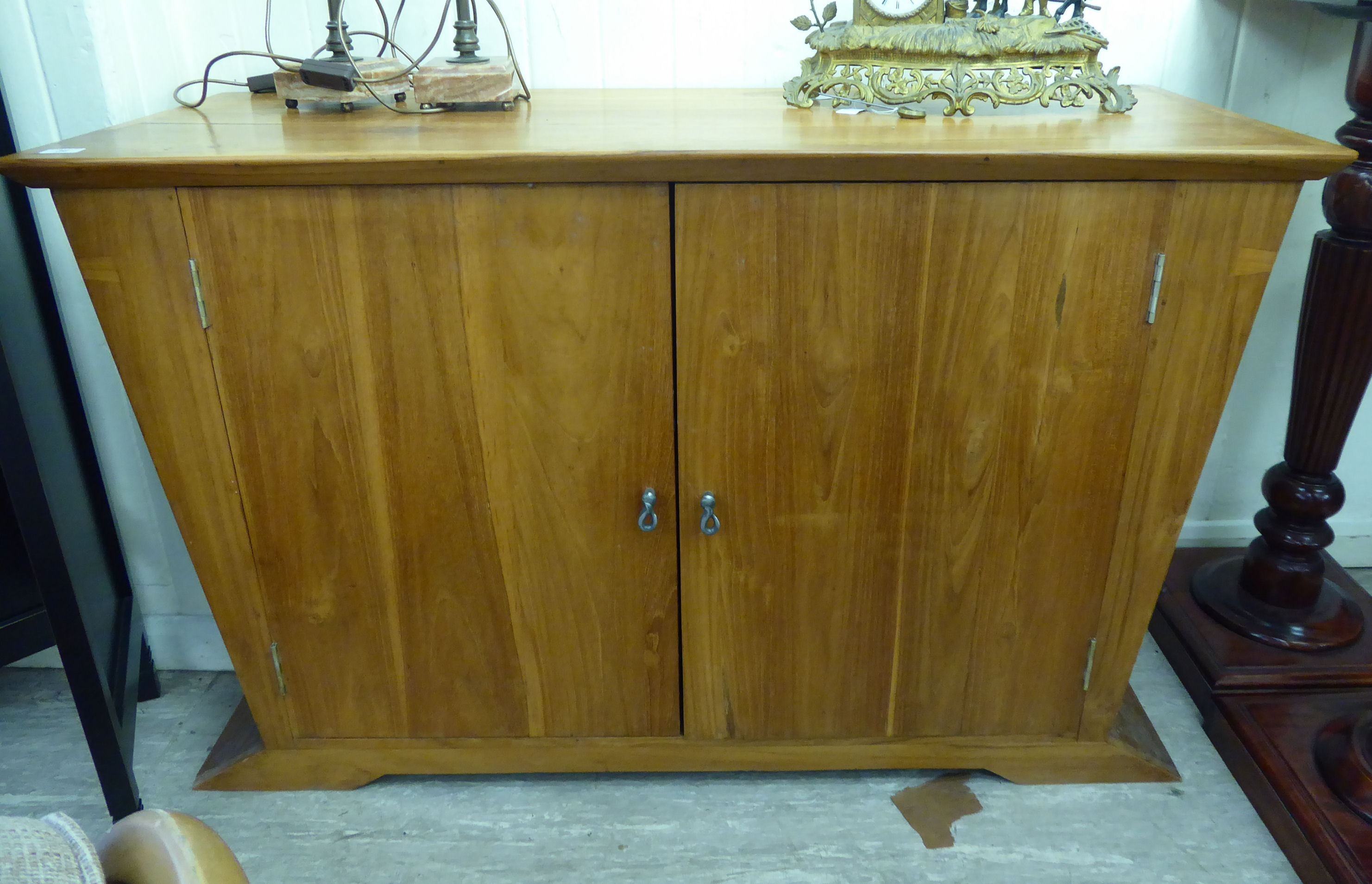 A modern honey coloured pine dresser base with tapered sides and a pair of full-height doors,