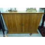 A modern honey coloured pine dresser base with tapered sides and a pair of full-height doors,