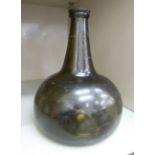 An early 19thC semi-opaque dark green glass wine bottle of squat,