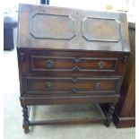 A 1930s oak bureau with applied mouldings, the fall flap enclosing a fitted interior,