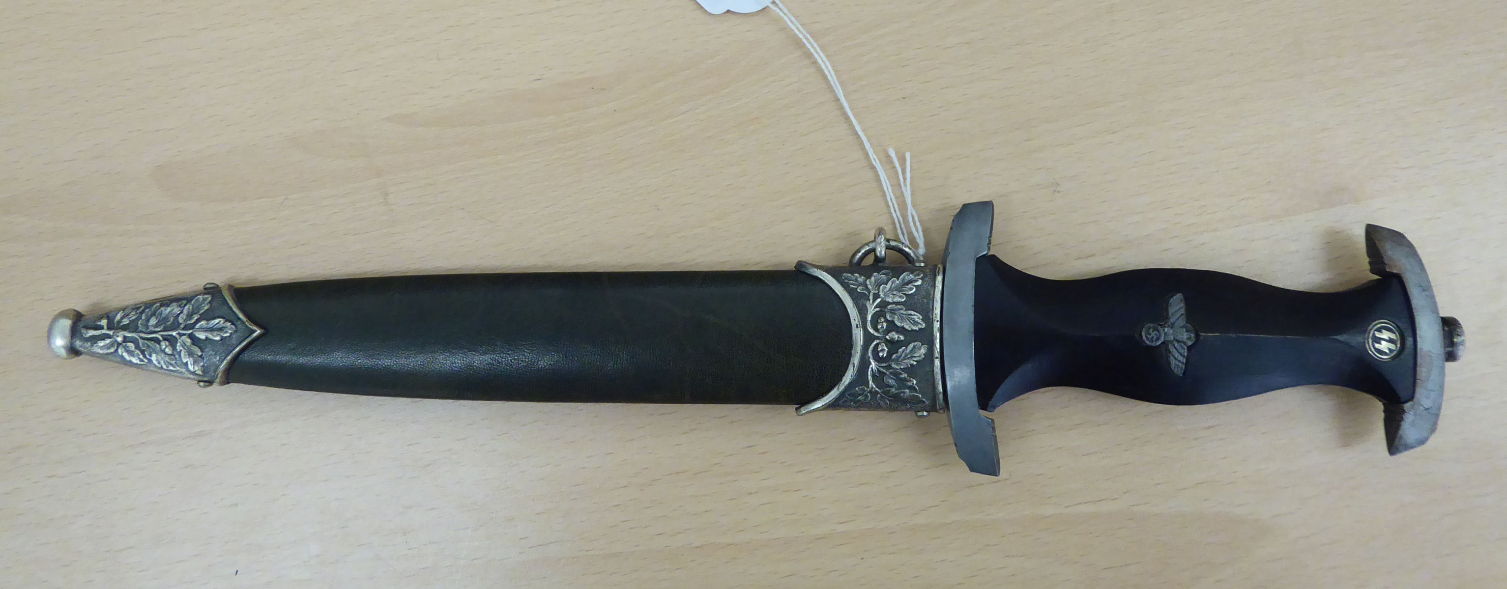 A replica SS dagger, the carved, ebonised wooden handgrip moulded with emblems, the 8.